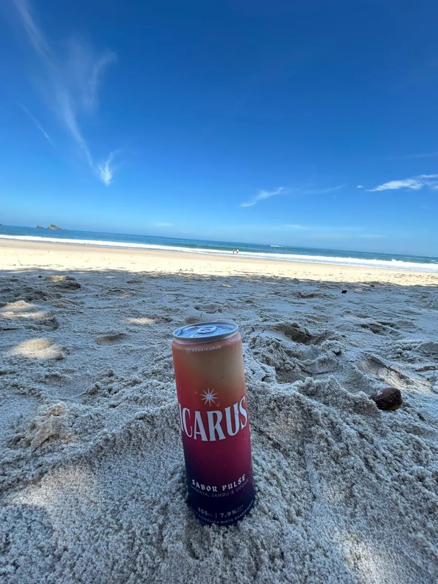 Lata de ICARUS na areia da praia, com o mar ao fundo